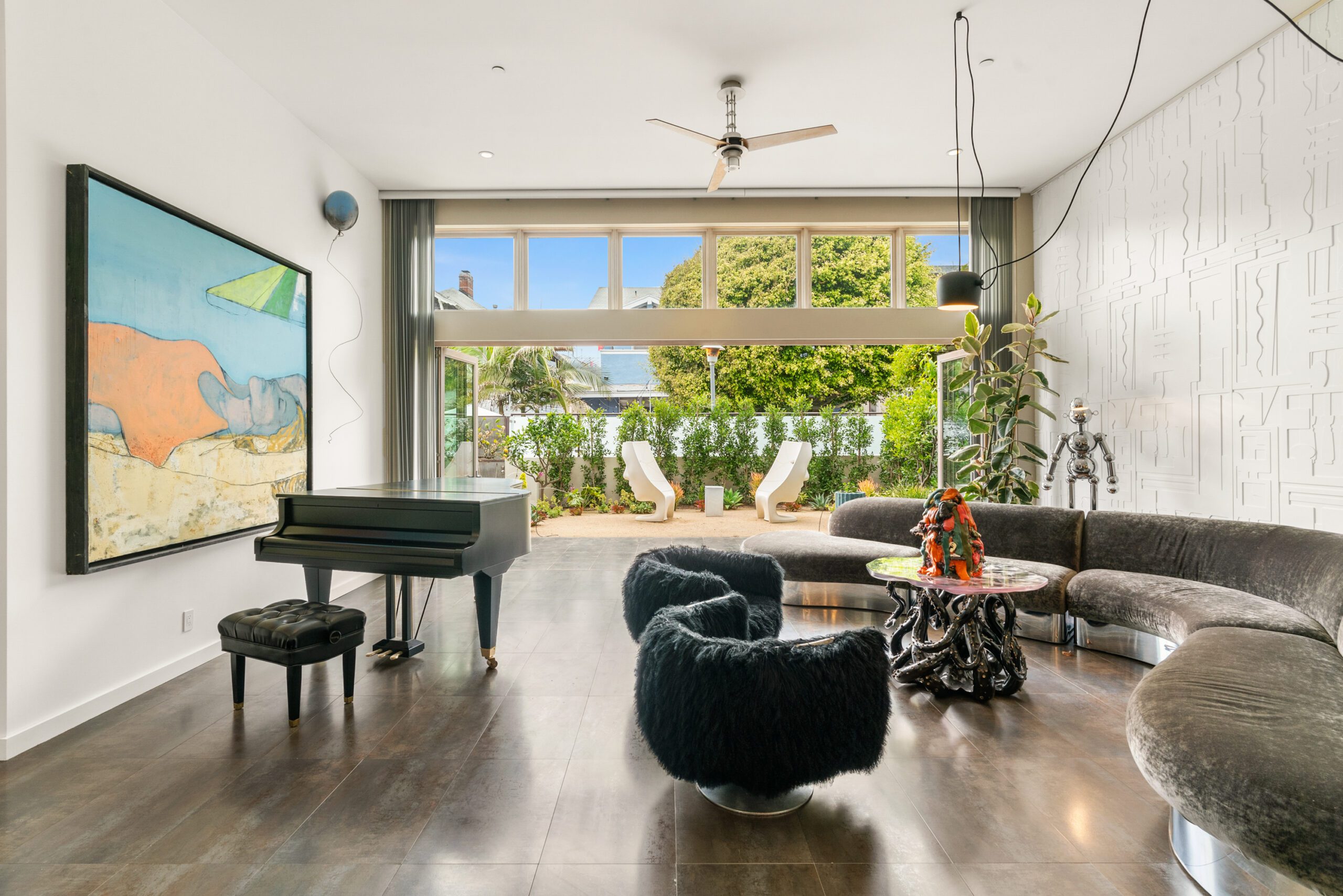 Spacious living room with grand piano, wraparound couch, and Alfresco Doors leading to the gorgeous outdoor patio.